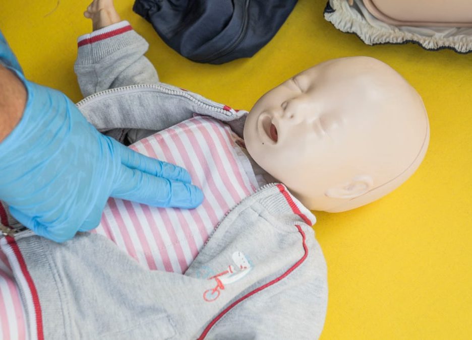 A person demonstrates infant CPR on a manikin, highlighting first aid techniques.